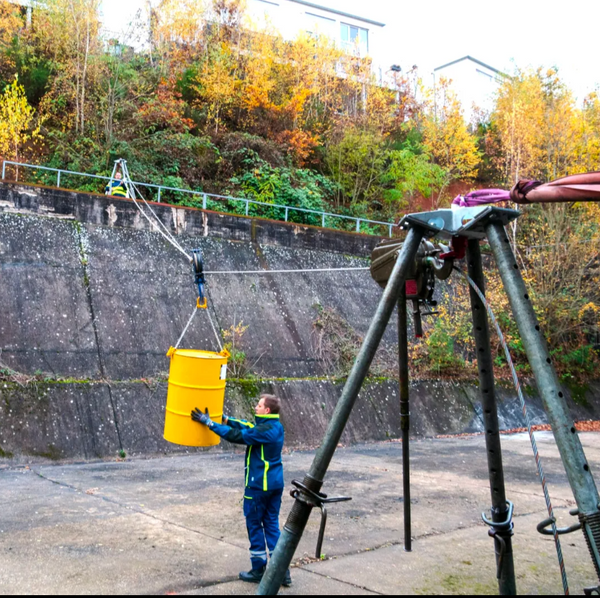Seilbahn mit Bautri-Dreibein: THW-Helfer transportiert ein Fass über eine Mauer