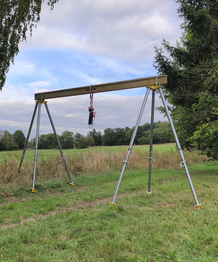 Portalhebung auf der Wiese: zwei Bautri-Dreibeine tragen einen Stahlträger mit Kettenzug